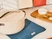 Caraway cream Dutch oven resting on a Navy tea towel beside crackers and cheese.