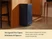 Caraway navy trash can standing beside a kitchen island.